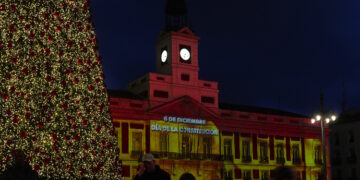 La bandera de España se proyecta sobre la Real Casa de Correos con un videomapping para conmemorar el Día de la Constitución.